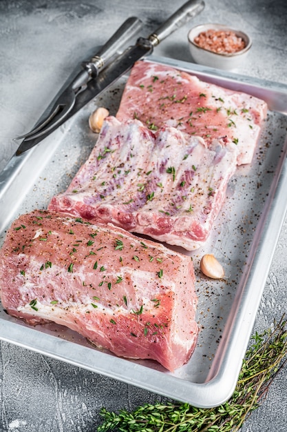 Coupes de porc crues, viande de longe, côtes levées et poitrine sur un plat de cuisson.