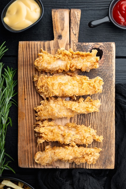 Coupes de poulet frit croustillant sur table en bois noir, vue du dessus.