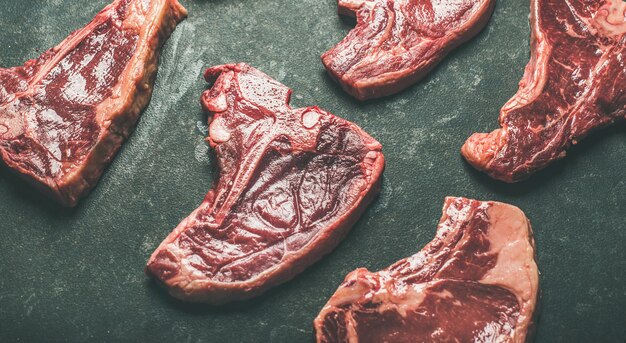 Coupes de steak de viande de boeuf cru sur fond noir