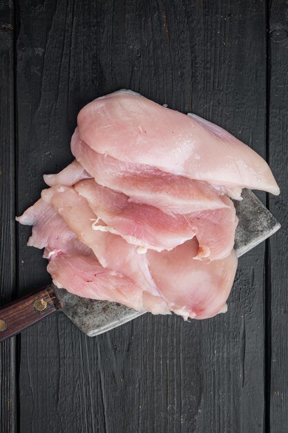 Photo coupes de viande de poulet crue, sur fond de table en bois noir, vue de dessus à plat