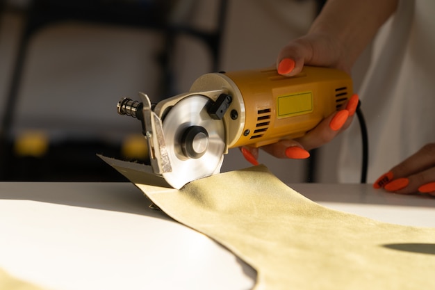 Coupeur électrique pour couper le textile en gros plan du travail manuel des femmes avec du tissu dans la salle de studio d'atelier