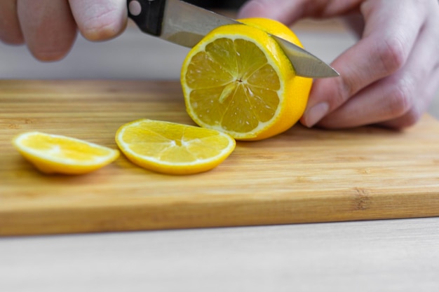 Coupez le citron. Les mains des hommes tranchent un citron.