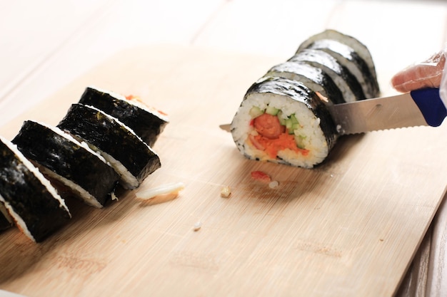 Coupez Le Kimbap (plat De Riz En Rouleau Coréen) Avec Un Couteau Bleu. Main De Femme Portant Un Gant En Plastique, Faisant Gimbap, Cut Kimbap, Korean Roll Gimbap (kimbob Ou Kimbap). Faire Du Kimbop étape Par étape