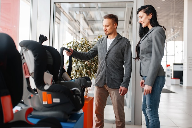 Photo couple achetant un siège d'auto pour enfant dans la salle d'exposition.