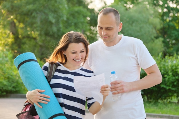 Couple actif mature en plein air pour un mode de vie sain, femme souriante et homme lisant une lettre de papier, émotion de joie bonheur