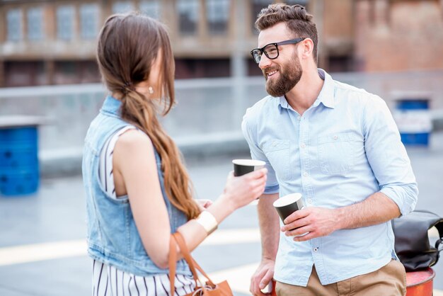 Couple d'affaires élégant parlant ensemble pendant la pause-café à l'extérieur sur l'aire de jeux sur le toit