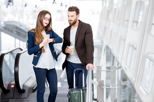 Couple d'affaires avec l'heure de contrôle des bagages se lever sur l'escalator à l'aéroport