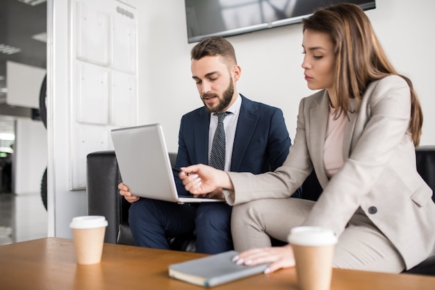 Couple d'affaires réussi travaillant avec ordinateur portable