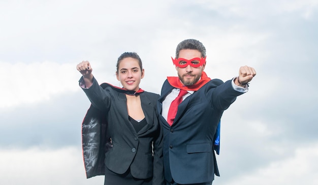 Couple d'affaires souriant en costume de super-héros sur fond de ciel