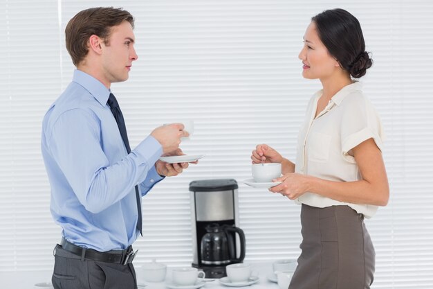 Couple d&#39;affaires avec des tasses de thé bavarder au bureau