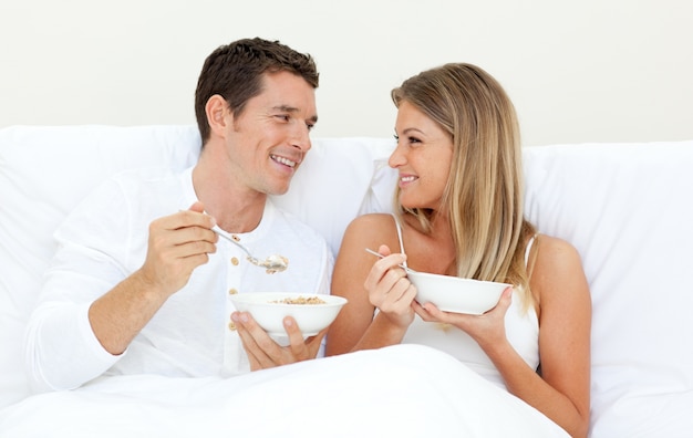 Couple affectueux prenant son petit déjeuner sur son lit