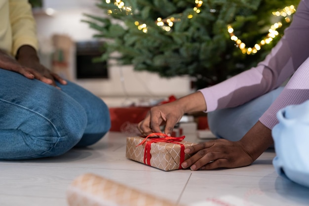 Photo un couple africain emballant des cadeaux de noël ensemble se préparant à la célébration de la veille du nouvel an à la maison