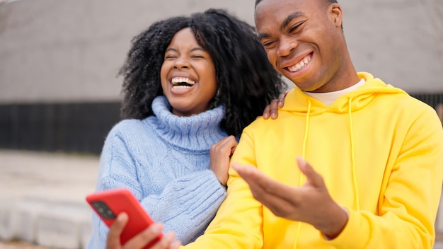 Un couple africain s'amusant avec son téléphone portable dans la rue.