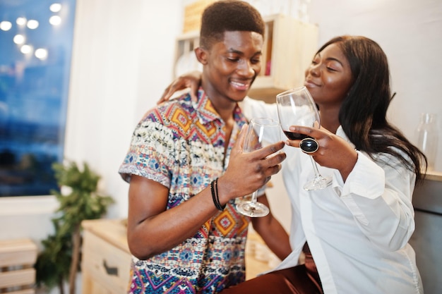 Couple afro-américain amoureux buvant du vin dans la cuisine à leur rendez-vous romantique