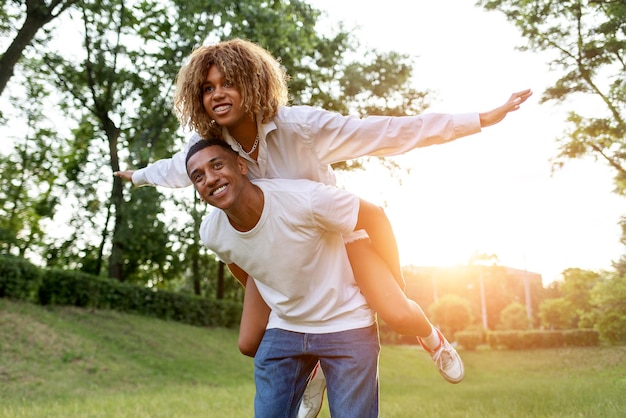 Un couple afro-américain amoureux court ensemble dans le parc et sourit un mec porte sa petite amie