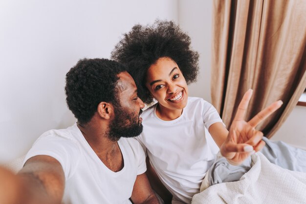 Couple afro-américain au lit Véritable belle et joyeuse paire d'amoureux à la maison