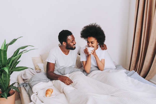 Couple afro-américain au lit Véritable belle et joyeuse paire d'amoureux à la maison