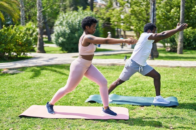 Photo couple afro-américain homme et femme faisant des exercices de yoga au parc
