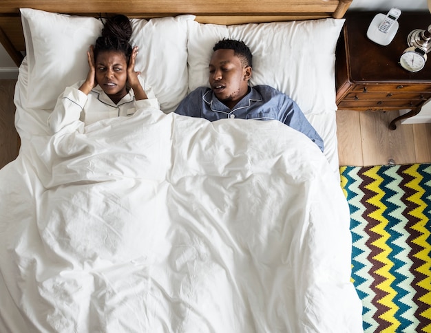 Couple afro-américain sur le lit, l&#39;homme ronfle et perturber le sommeil de la femme