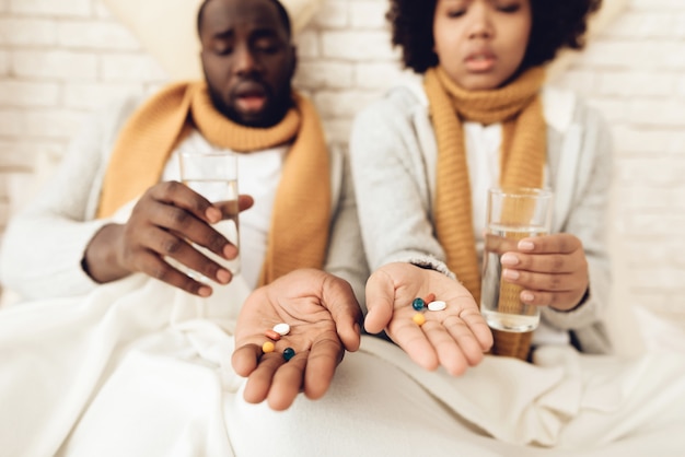 Couple afro-américain malade boire des pilules.