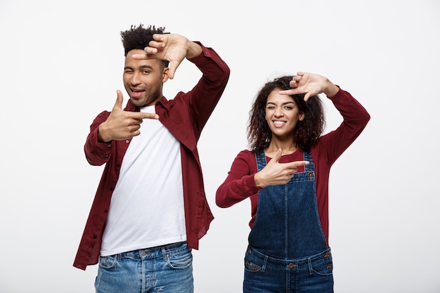 Couple afro-américain à la recherche à travers un cadre de doigt et souriant