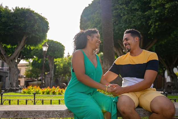 Couple afro-américain romantique assis sur un banc