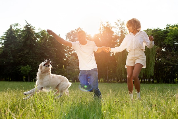 Un couple d'Afro-Américains heureux se promènent et courent ensemble avec un chien dans le parc en été.