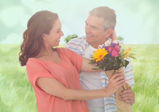 Couple d'âge moyen avec des fleurs dans un pré flou