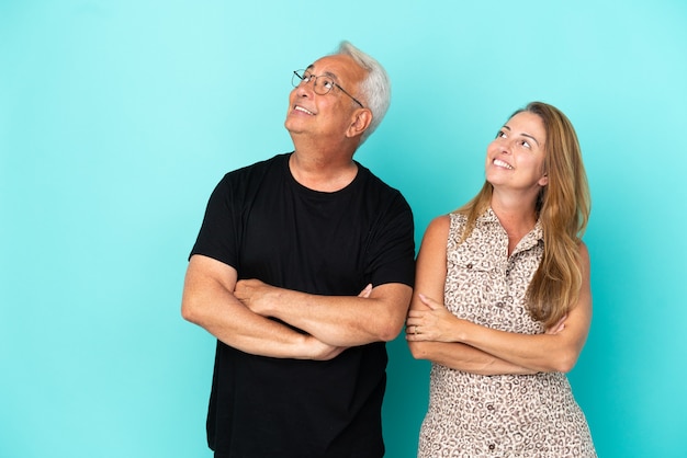 Couple d'âge moyen isolé sur fond bleu en levant tout en souriant