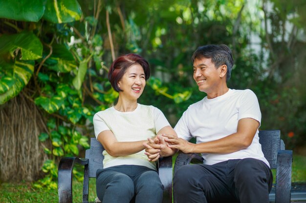 Photo couple d'âge moyen se détendre assis sur un banc dans l'arrière-cour.