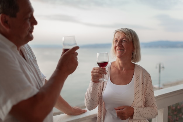 Un couple d'âge moyen souriant sur une terrasse près de la mer