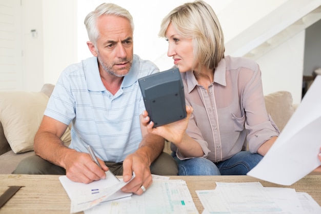 Couple d&#39;âge mûr concentré avec factures et calculatrice à la maison