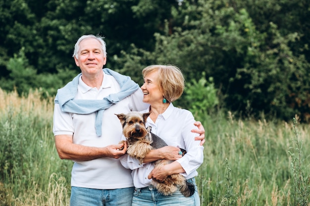 Un couple d'âge mûr marche avec un chien dans un parc