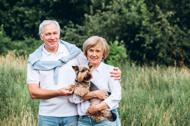 Un couple d'âge mûr marche avec un chien dans un parc