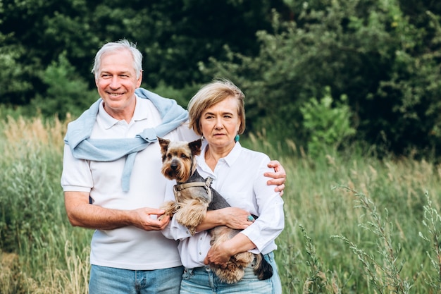 Un couple d'âge mûr marche avec un chien dans un parc