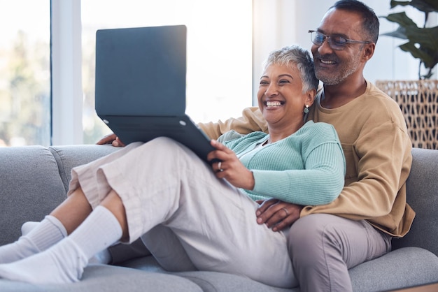 Couple d'âge mûr ordinateur portable et se détendre sur le canapé dans le salon maison et maison sur abonnement en streaming achats en ligne et téléchargement de médias Internet Heureux homme femme et technologie informatique dans le salon