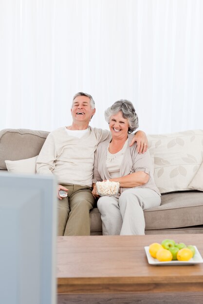 Couple d&#39;âge mûr regarder la télévision dans leur salon