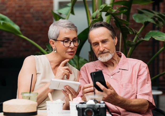 Couple d'âge mûr utilisant leur smartphone tout en étant assis à l'extérieur