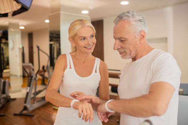 Couple d'âge mûr vérifiant les pulsomètres dans la salle de sport et à intéressé