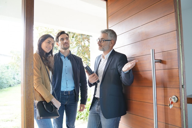 Couple avec agent immobilier visitant une maison moderne