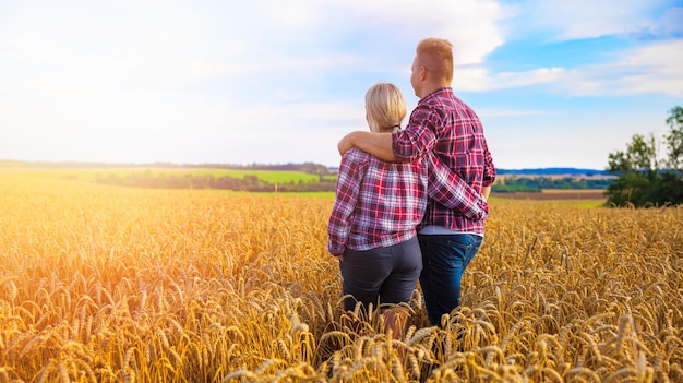 Couple d'agriculteurs debout dans un champ de blé ensemble