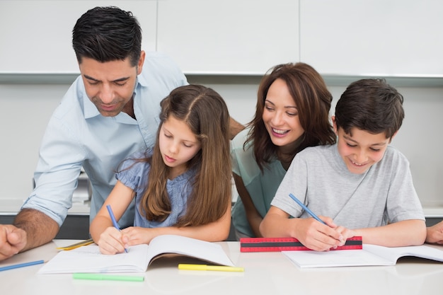 Couple aidant les enfants avec leurs devoirs dans la cuisine