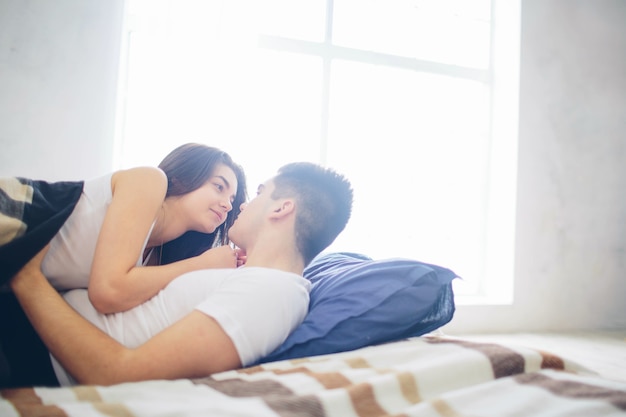 Un couple aimant est allongé sur le lit. Chambre lumineuse et confortable