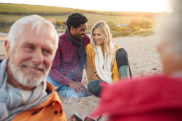 Couple aimant se détendre au coin du feu avec des parents âgés en vacances à la plage d'hiver