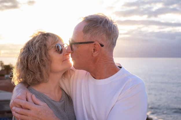 Un couple d'aînés heureux, mûrs et romantiques s'embrassent sur le rivage pour exprimer leur amour.