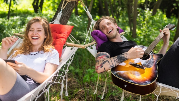 Couple allongé sur des hamacs Jeune homme joue de la guitare