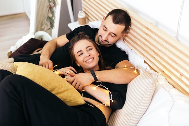 Couple allongé sur le lit enveloppé dans une couverture étreignant