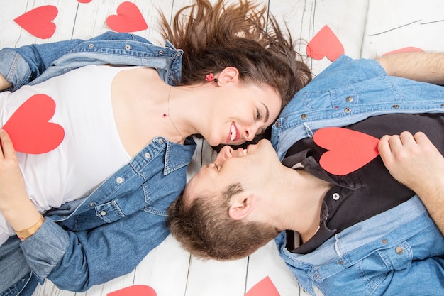 Couple allongé sur le plancher en bois avec des coeurs