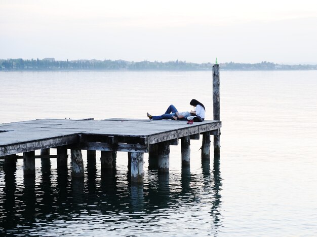 Couple allongé près du quai en bois sur un beau lac