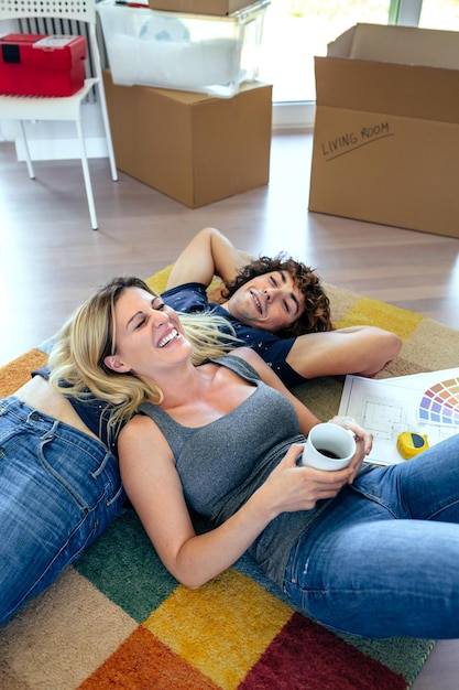 Couple allongé sur le tapis de leur nouvelle maison